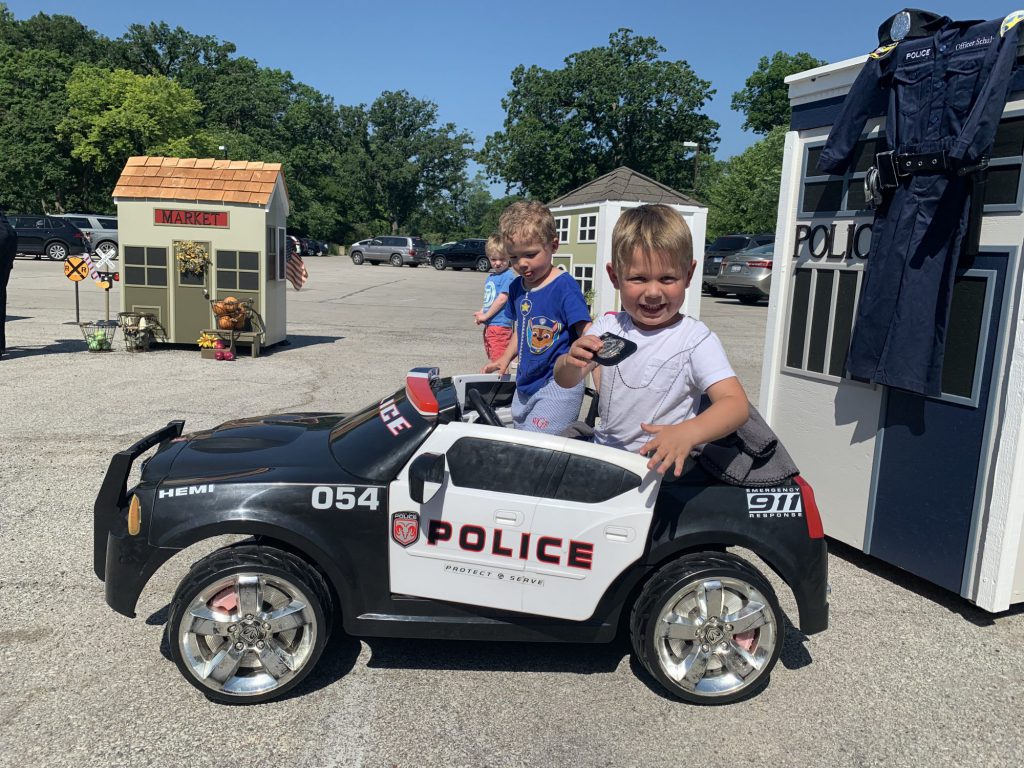 two young boys sitting in a toy police car