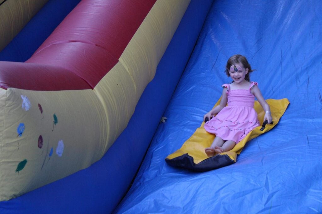 Young girl sliding down an inflatable slide and laughing