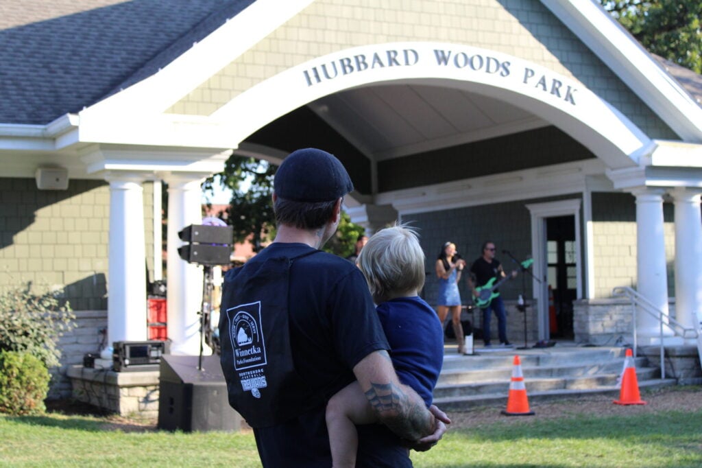Man standing and holding young boy, facing away from camera and towards concert
