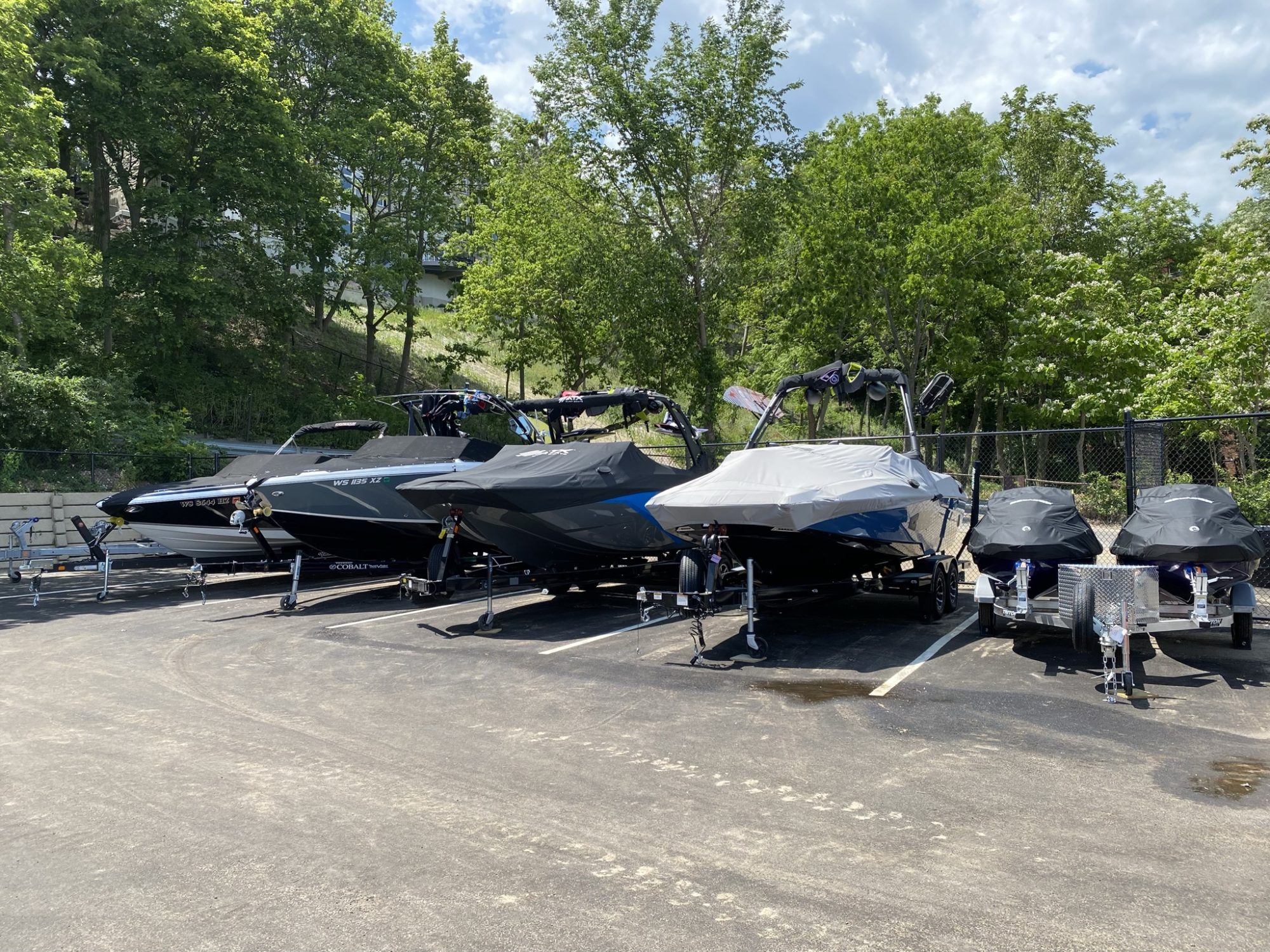 four motorized boats and two jet skis sitting in fenced-in storage at Lloyd Beach