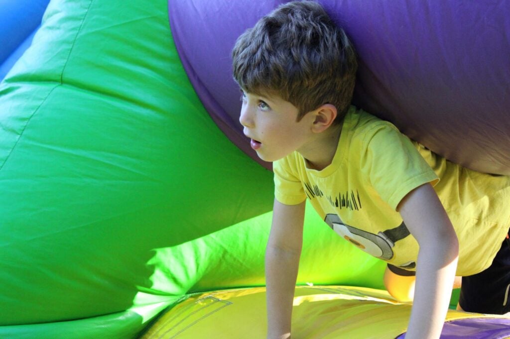 Young boy climbing out of bouncy house and looking up outside