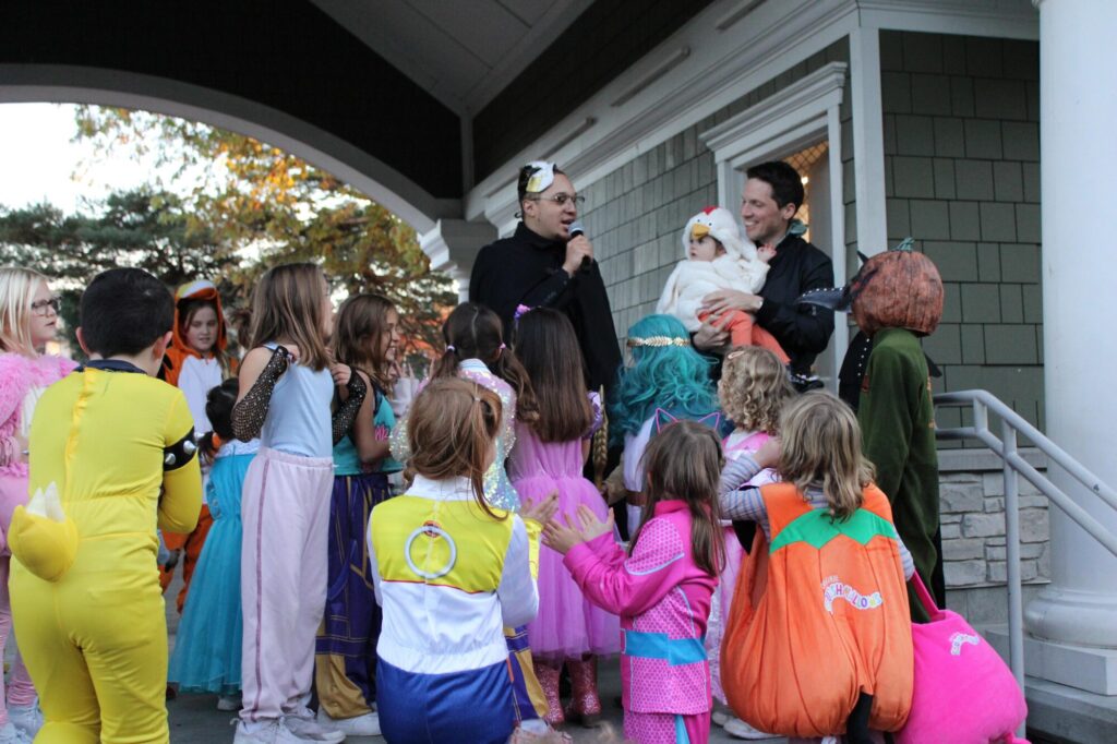 Man in costume singing to group of children in Halloween costumes
