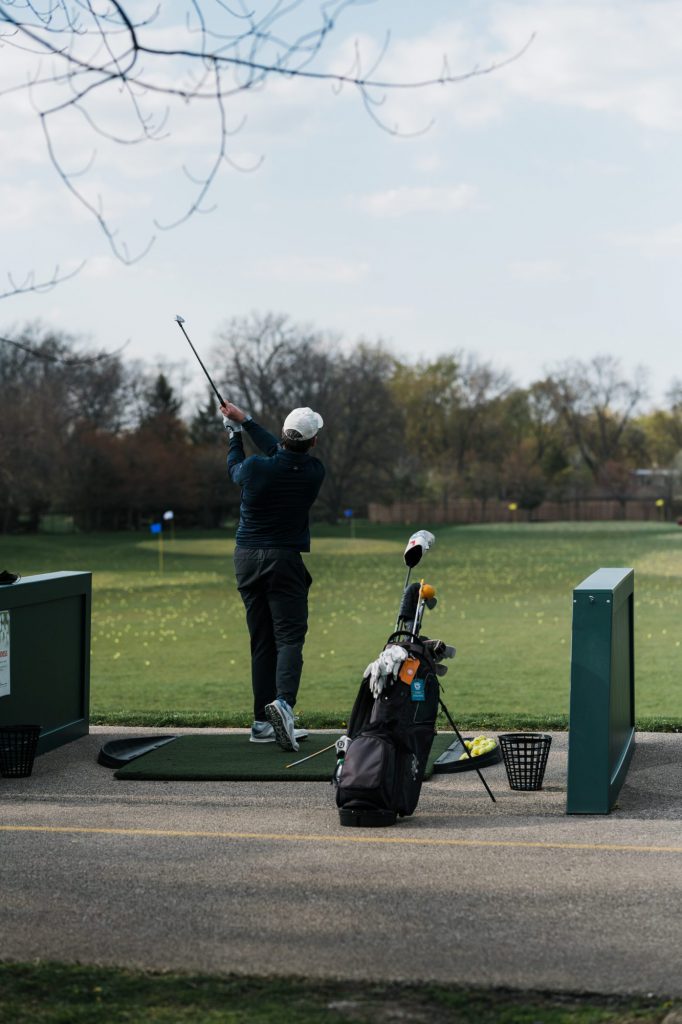 A man practicing his golf swing at the golf range.