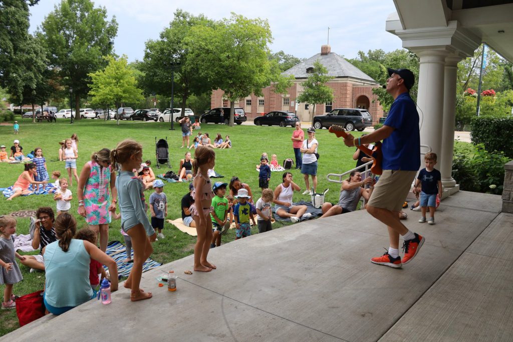Children listening to a man sing with a guitar.
