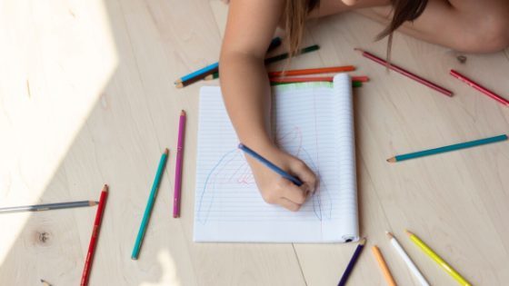 young girl drawing with colored pencils