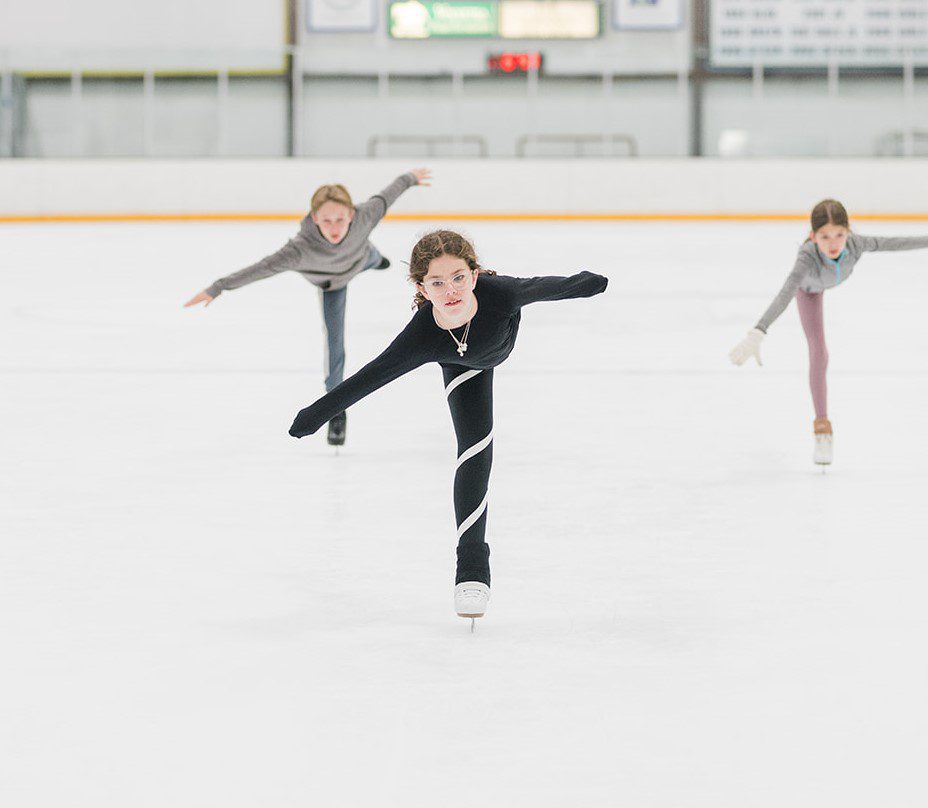 One middle school aged boy and two middle school aged girls practicing arabesques.