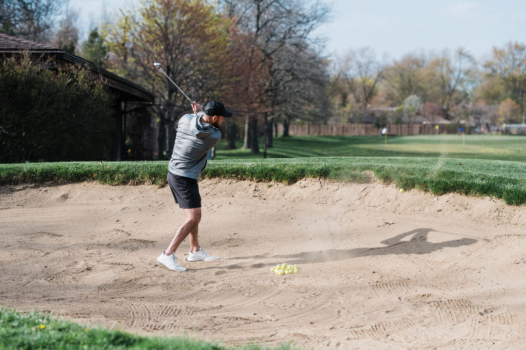 man practicing in golf sand bunker